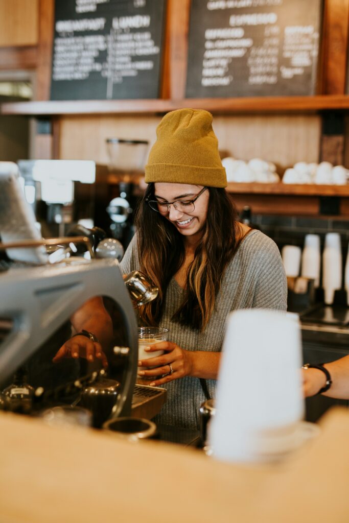 Smiling cafe worker making coffee